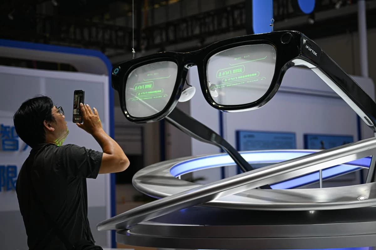 A visitor photographs a pair of large AI smart glasses on display at a technology expo