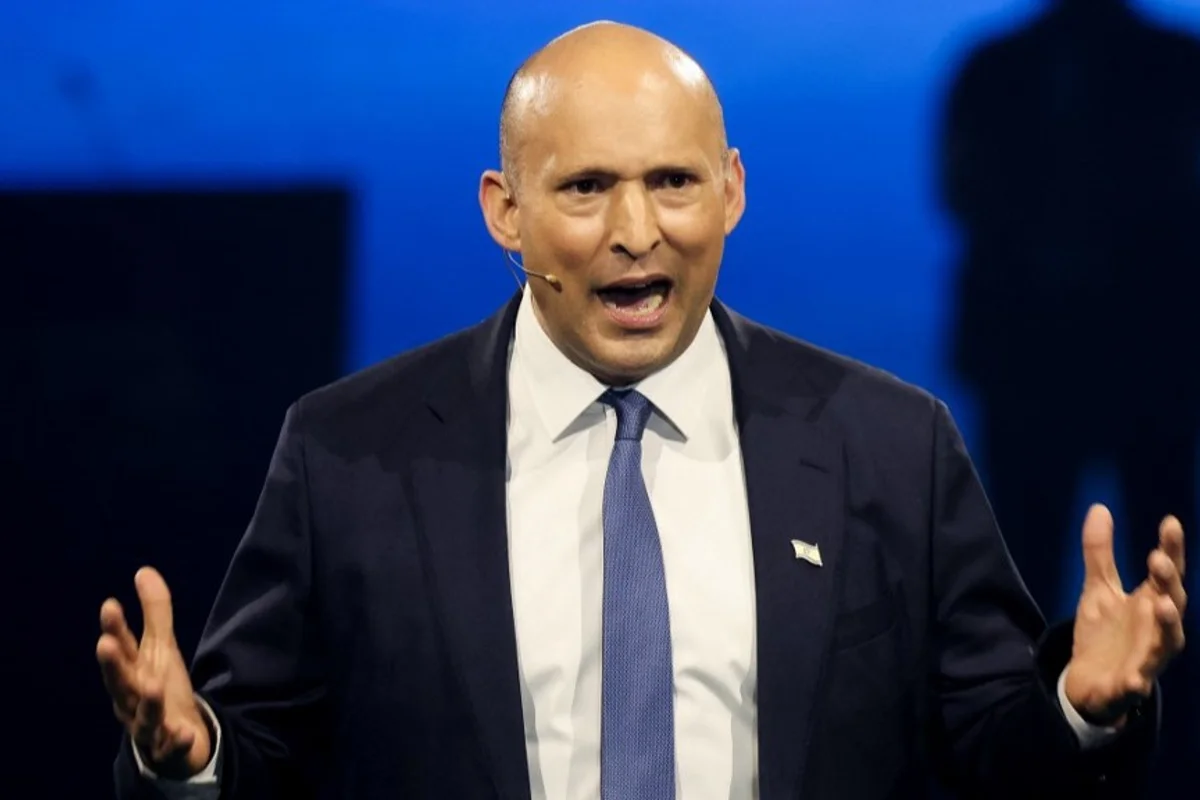 Naftali Bennett speaks animatedly on stage with a headset microphone