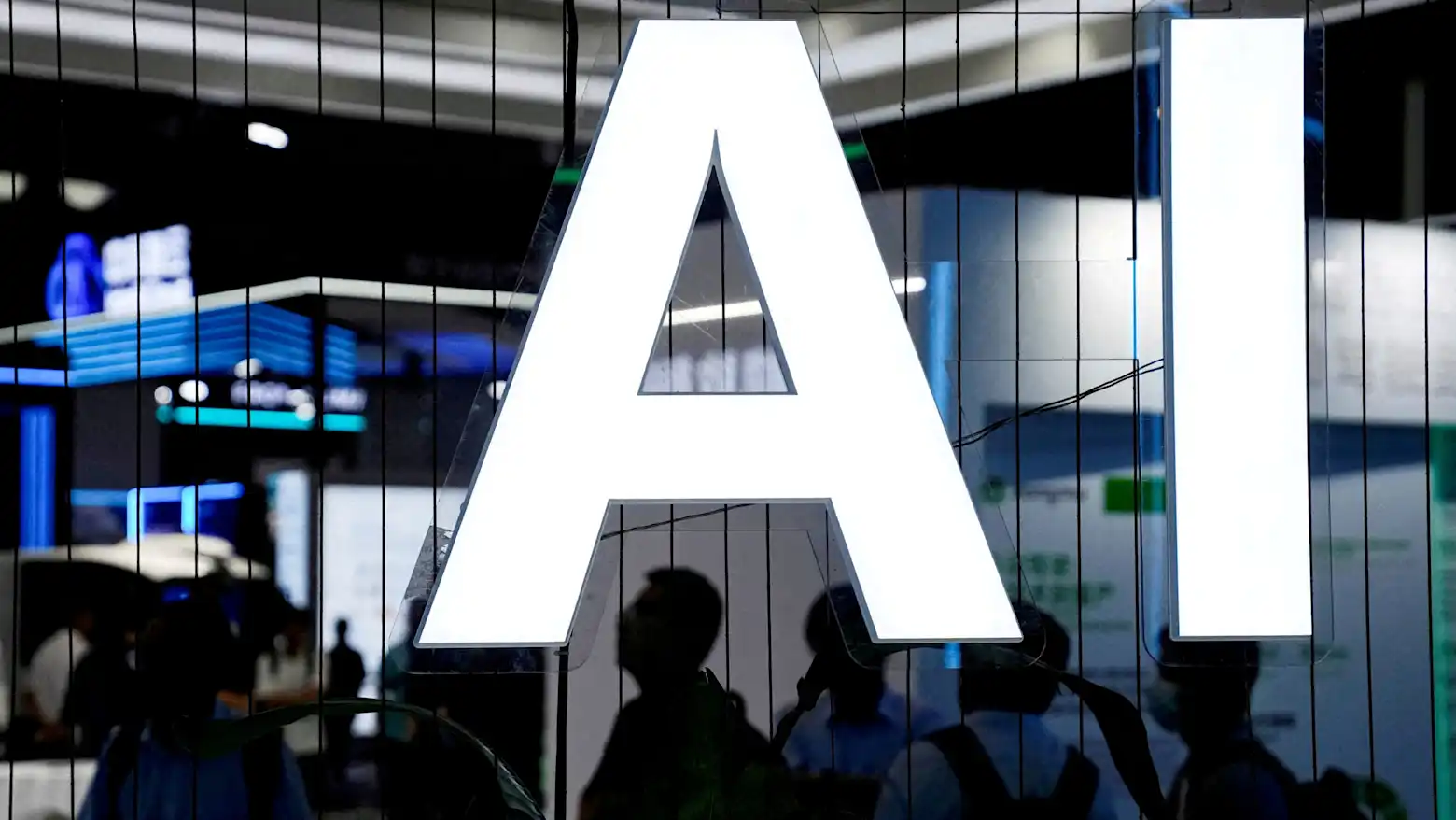 A lit AI sign on display at a technology exhibition, with visitors silhouetted beneath it