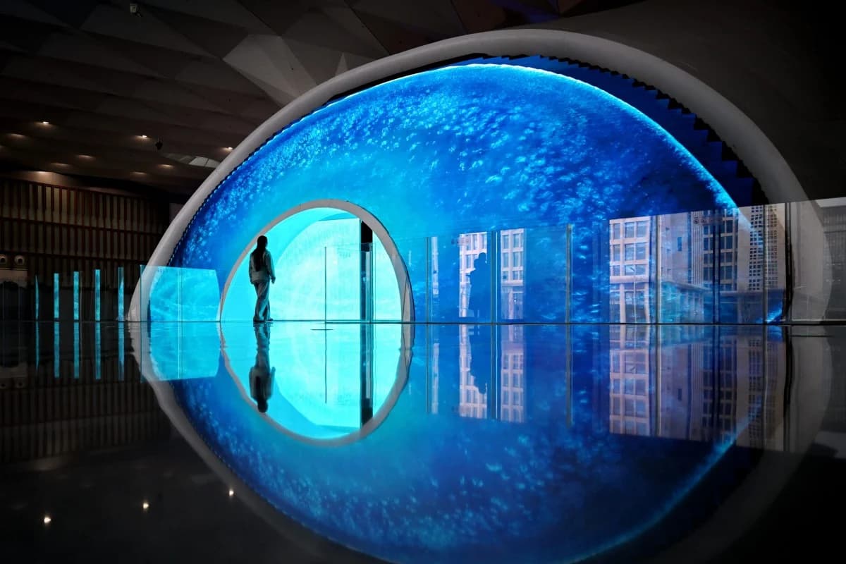 A visitor walks through an illuminated blue data-themed exhibit at a technology showcase