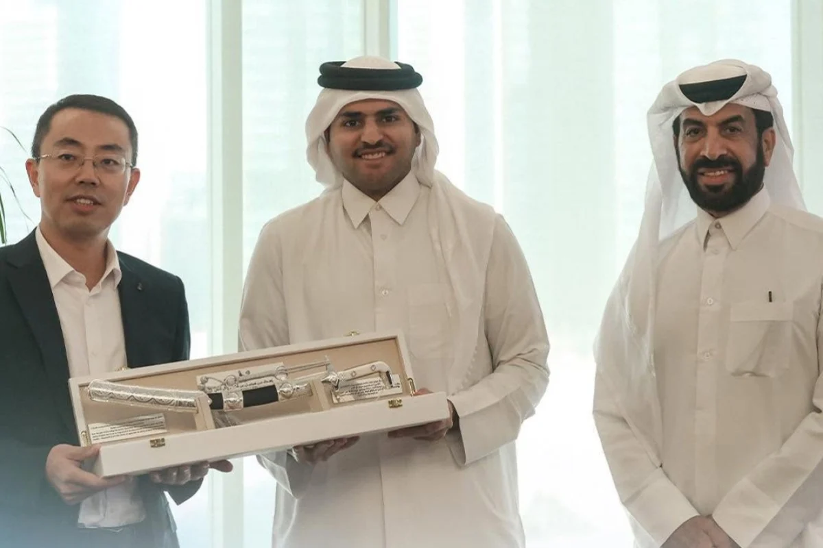 A Chinese executive and Qatari officials pose with a ceremonial gift at a contract signing