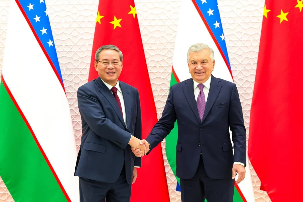 Chinese Premier Li Qiang shakes hands with Uzbekistan's president in front of national flags