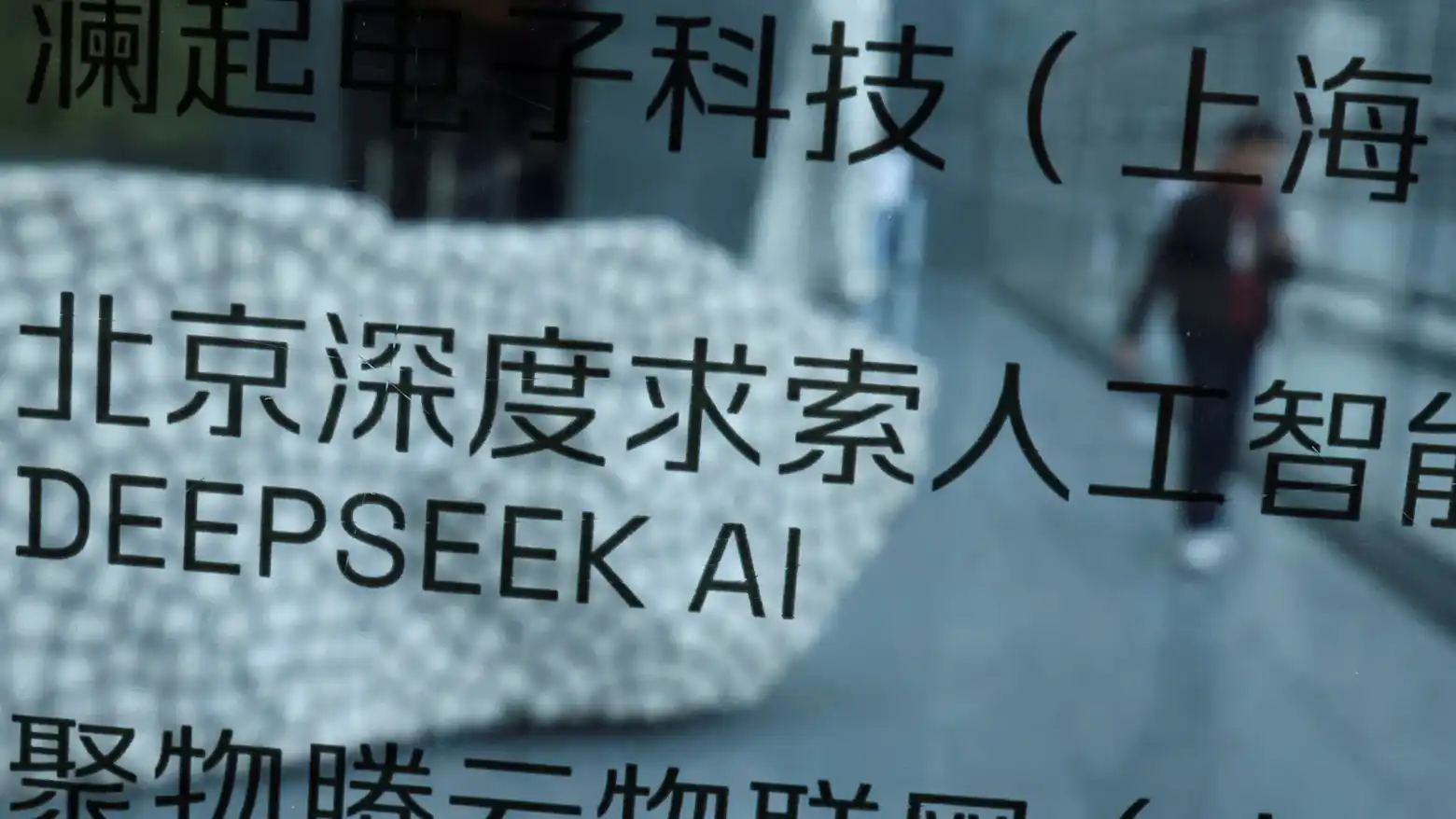 A reflection shows the DeepSeek AI logo on a glass panel