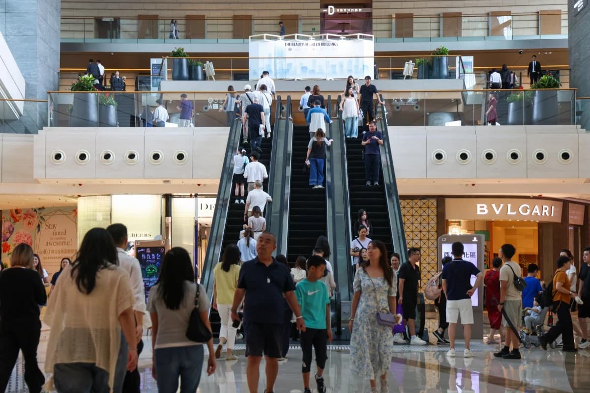 Shoppers move through a crowded Hong Kong shopping mall with visible overhead surveillance cameras