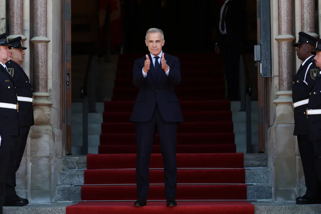Canadian Prime Minister Mark Carney applauds while standing on red-carpeted steps