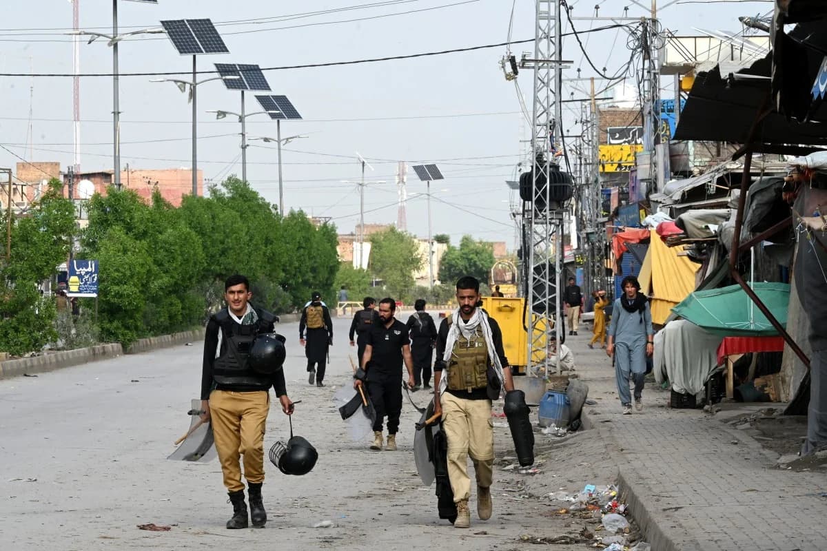 Security forces in riot gear walk down a street in Pakistan