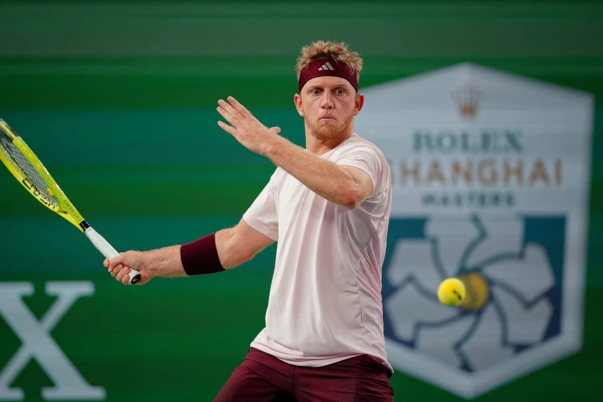 A tennis player in maroon and white makes a forehand shot in front of Shanghai Masters signage