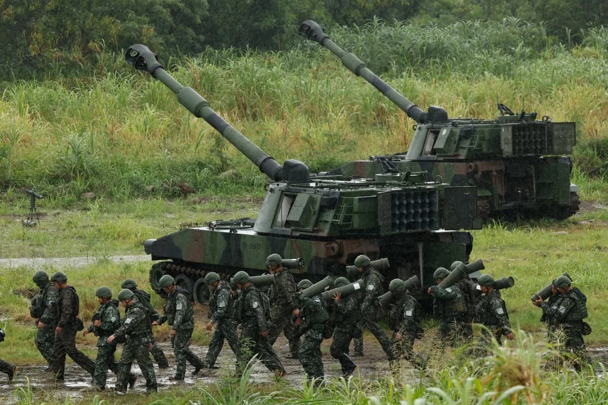 Taiwanese soldiers march past self-propelled howitzers during a military exercise