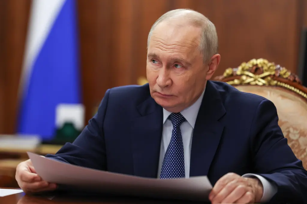 Russian President Vladimir Putin reviews documents at a desk in the Kremlin